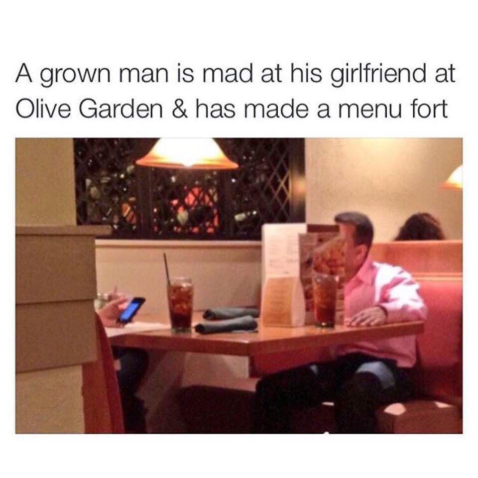 A grown man is mad at his girlfriend at Olive Garden & has made a menu fort.