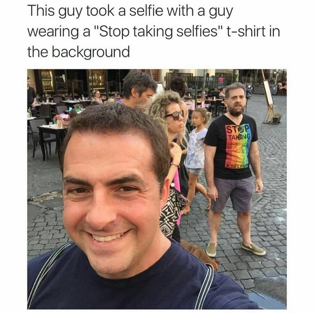 This guy took a selfie with a guy weaving a "Stop taking" t-shirt in the background.